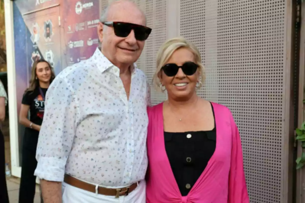 José Carlos Bernal i Carmen Borrego somrient i portant ulleres de sol en un esdeveniment a l’aire lliure, ella porta un conjunt rosa i negre i ell una camisa blanca estampada i pantalons blancs. José Carlos Bernal i Carmen Borrego somrient i portant ulleres de sol en un esdeveniment a l’aire lliure, ella porta un conjunt rosa i negre i ell una camisa blanca estampada i pantalons blancs.