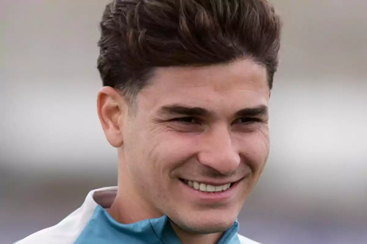 A young man smiling with dark, short hair, wearing a sports jacket.