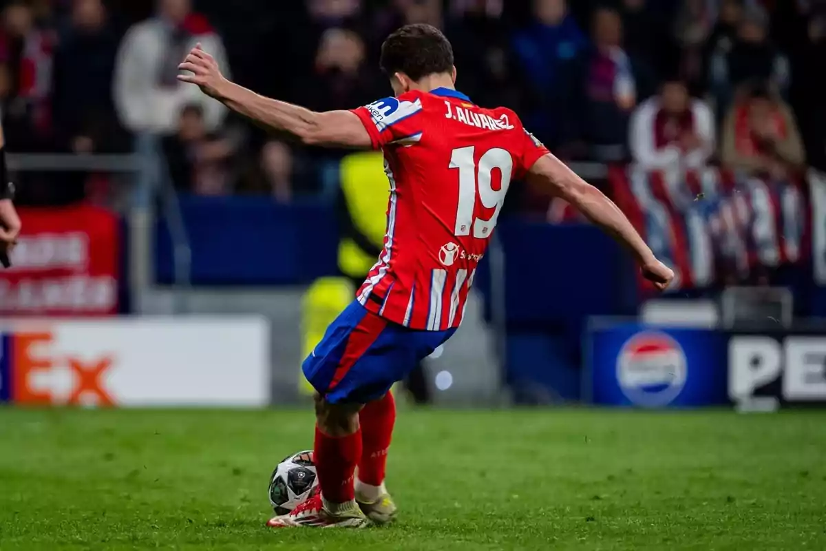 Soccer player in a red and blue jersey number 19 kicking a ball in a stadium. Soccer player in a red and blue jersey number 19 kicking a ball in a stadium.