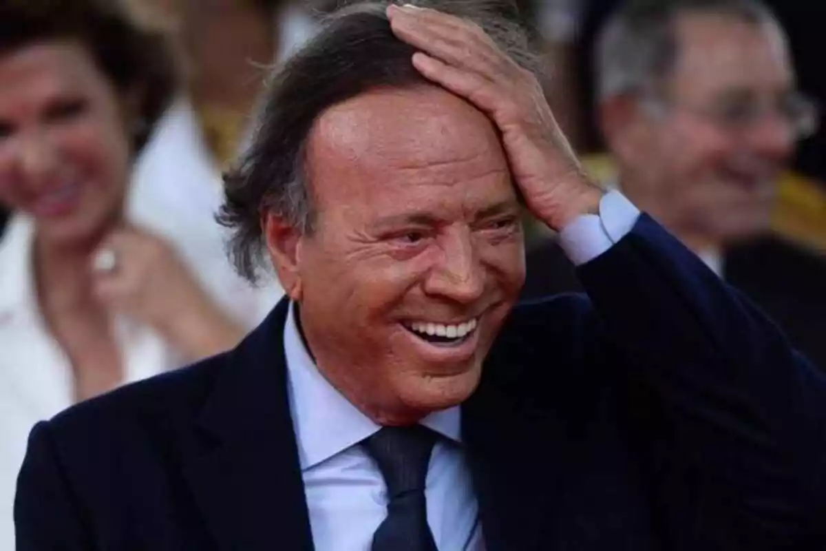 Julio Iglesias with his hand on his head and laughing