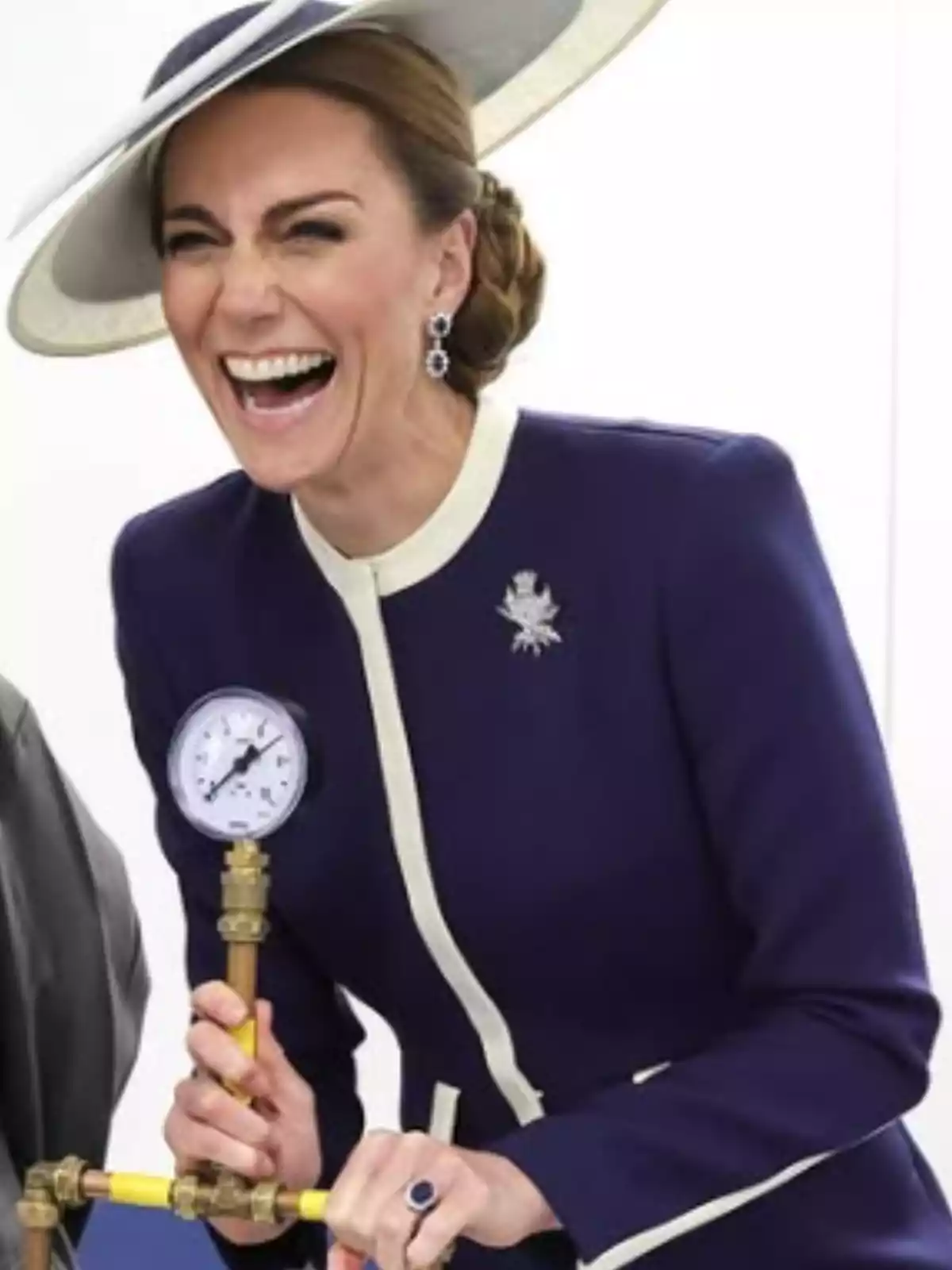 Una dona somrient amb un barret elegant i un vestit blau fosc sosté un manòmetre. Una dona somrient amb un barret elegant i un vestit blau fosc sosté un manòmetre.