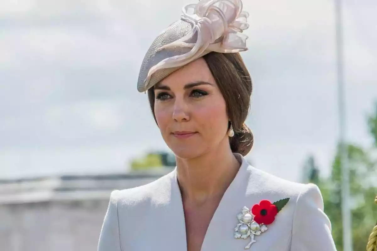 Kate Middleton seria amb un tocat beix, els cabells recollits i un pin amb una flor Kate Middleton seria amb un tocat beix, els cabells recollits i un pin amb una flor