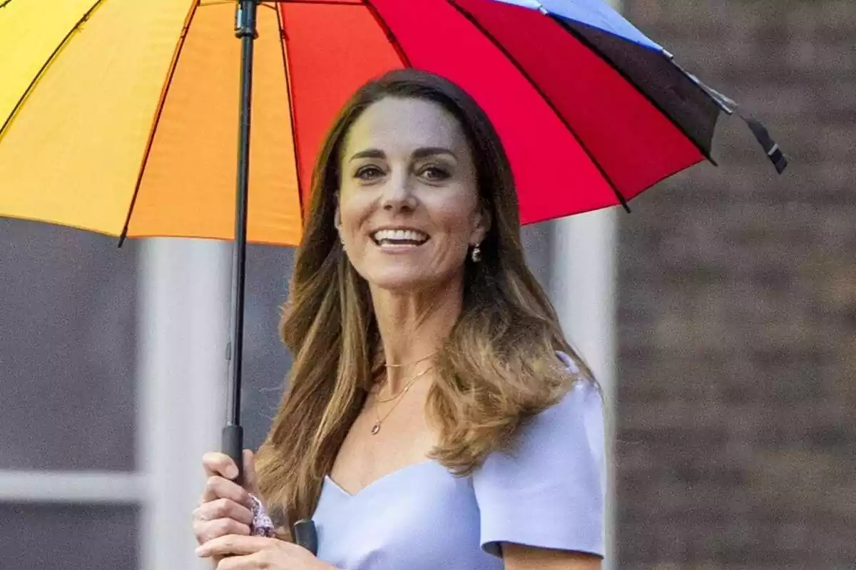 Kate Middleton smiling in a blue dress holding a colorful umbrella Kate Middleton smiling in a blue dress holding a colorful umbrella