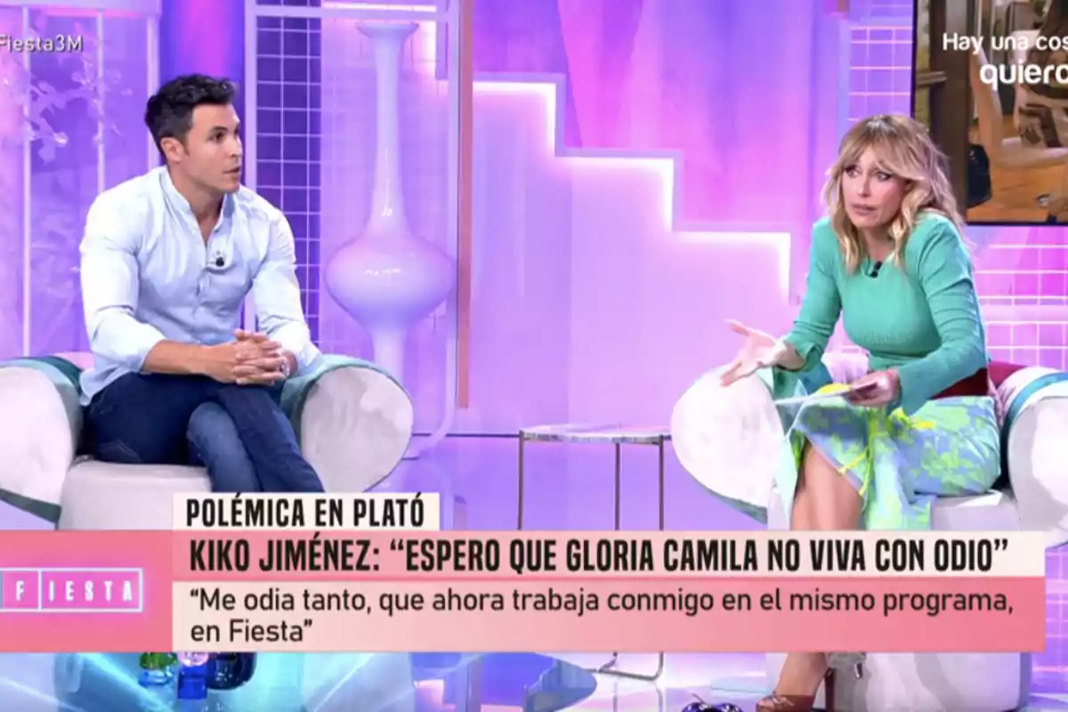 En un plató de televisió, Kiko Jiménez y Emma García estan assegudes en butaques blanques, conversant en un ambient il·luminat amb llums roses i morades, mentre a la part inferior de la imatge es mostra un text sobre una polèmica relacionada amb un programa anomenat En un plató de televisió, Kiko Jiménez y Emma García estan assegudes en butaques blanques, conversant en un ambient il·luminat amb llums roses i morades, mentre a la part inferior de la imatge es mostra un text sobre una polèmica relacionada amb un programa anomenat