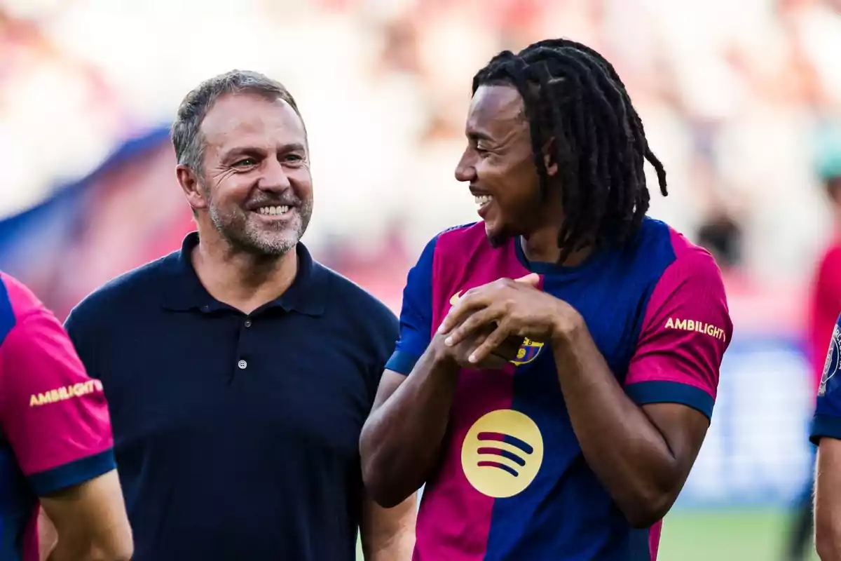 Dos personas sonrientes conversando, una de ellas con una camiseta de fútbol del FC Barcelona. Dos personas sonrientes conversando, una de ellas con una camiseta de fútbol del FC Barcelona.