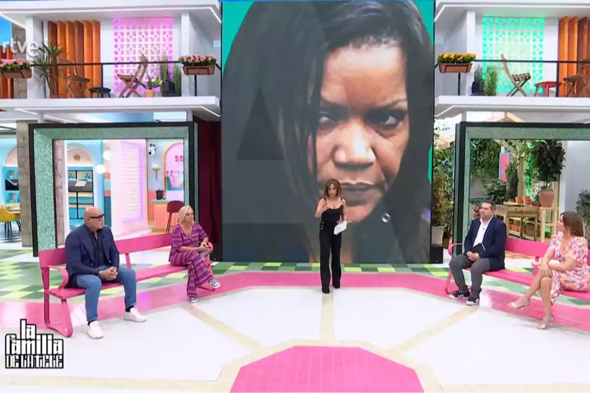 Un grup de persones està assegut en un plató de televisió acolorit, amb una gran pantalla darrere mostrant el rostre d'una dona. Captura de 'La Família de la Tele'. Un grup de persones està assegut en un plató de televisió acolorit, amb una gran pantalla darrere mostrant el rostre d'una dona. Captura de 'La Família de la Tele'.