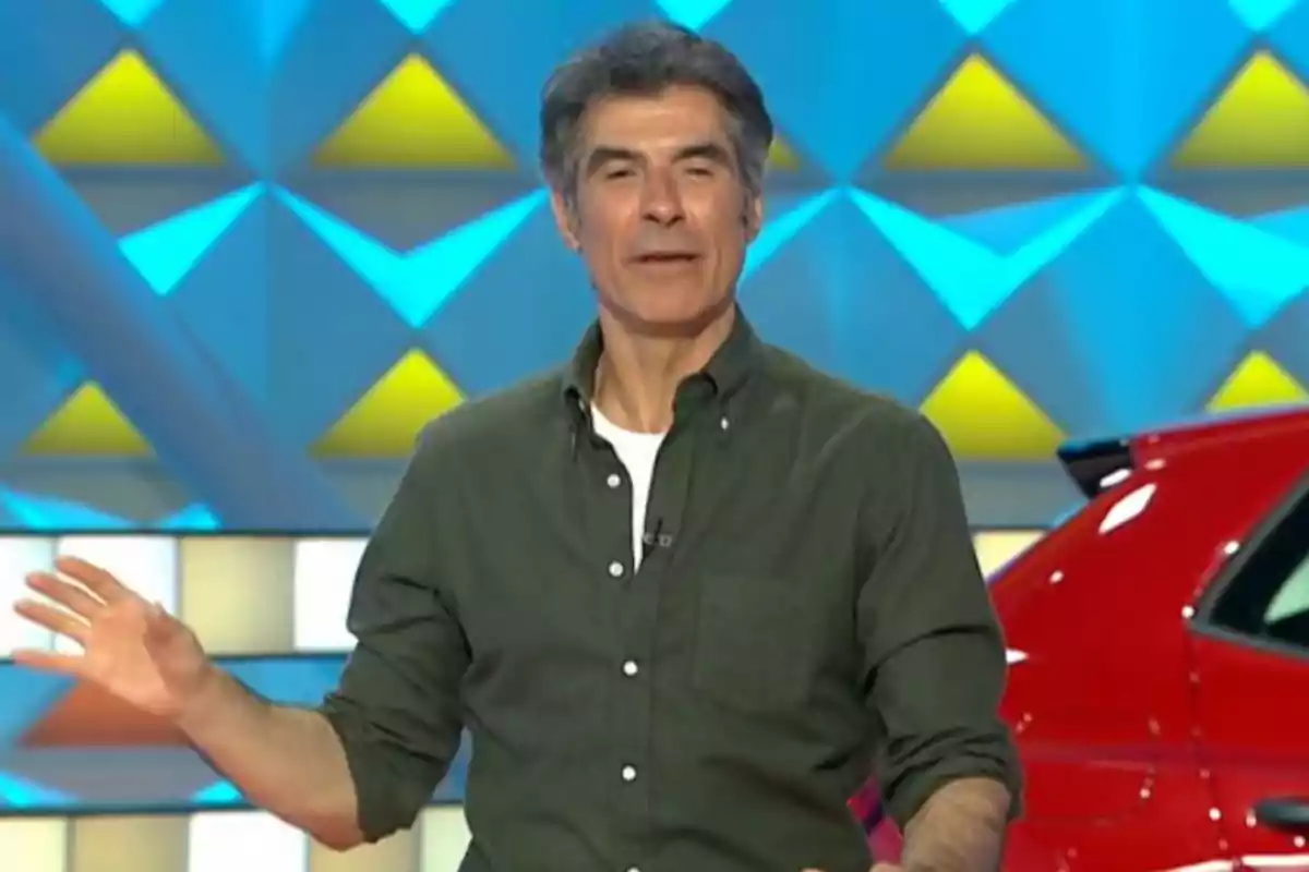 Jorge Fernández amb camisa verd fosc i samarreta blanca de fons en un plató colorit al costat d’un cotxe vermell. Captura de ‘La Ruleta de la Suerte’. Jorge Fernández amb camisa verd fosc i samarreta blanca de fons en un plató colorit al costat d’un cotxe vermell. Captura de ‘La Ruleta de la Suerte’.