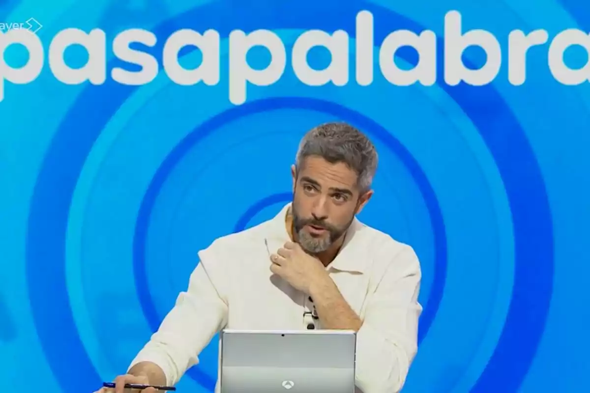 Roberto Leal amb barba i cabell canós està assegut davant d'un ordinador portàtil en un plató de televisió amb un fons blau que té el text Roberto Leal amb barba i cabell canós està assegut davant d'un ordinador portàtil en un plató de televisió amb un fons blau que té el text