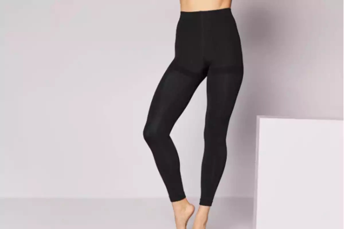 Persona vestint leggings negres en un fons neutre.