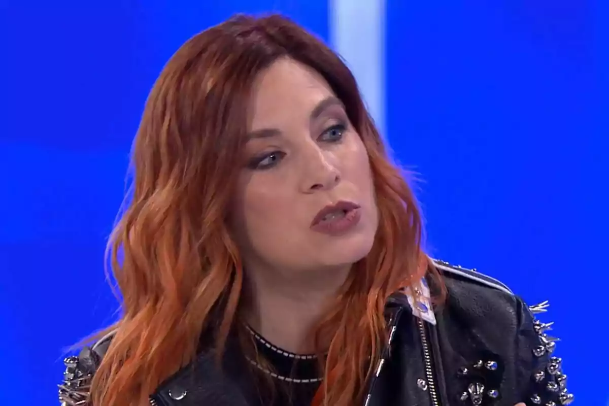 Leire Martínez de cabello pelirrojo con chaqueta de cuero negro en un fondo azul en Hay una cosa que te quiero decir.