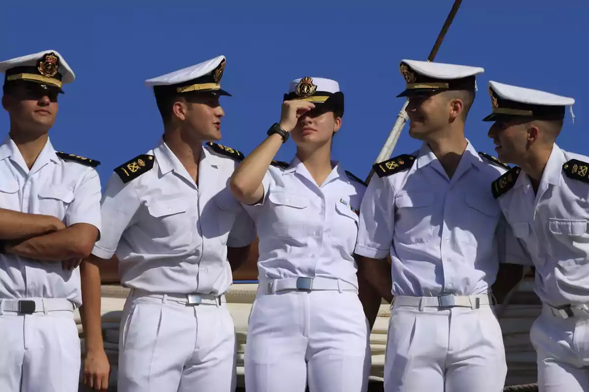 Un grup de cadets navals en uniforme blanc posant junts sota un cel blau. Un grup de cadets navals en uniforme blanc posant junts sota un cel blau.