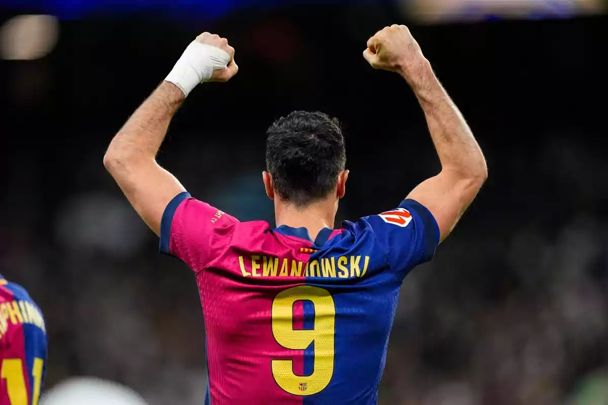 Jugador de futbol celebrant amb els braços enlaire mentre vesteix una samarreta blava i rosa amb el número 9. Jugador de futbol celebrant amb els braços enlaire mentre vesteix una samarreta blava i rosa amb el número 9.