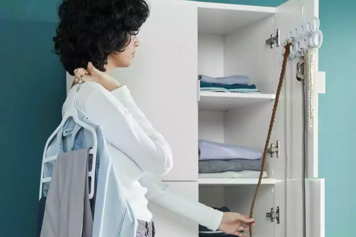 Persona de cabells arrissats organitzant roba i accessoris en un armari blanc amb prestatges i penjadors per penjar peces i cinturons Persona de cabells arrissats organitzant roba i accessoris en un armari blanc amb prestatges i penjadors per penjar peces i cinturons