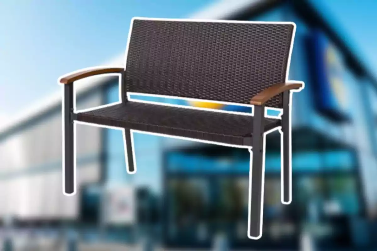 Banc de vímet fosc amb braços de fusta davant d'un fons desenfocat d'un edifici modern. Banc de vímet fosc amb braços de fusta davant d'un fons desenfocat d'un edifici modern.