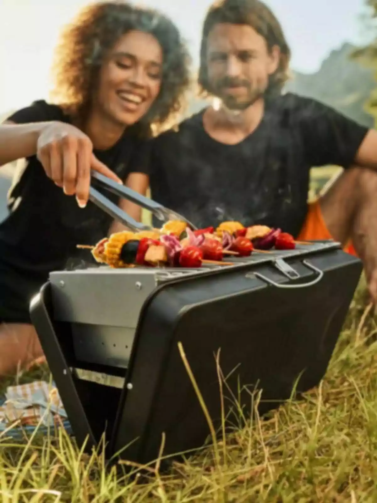 Una parella gaudeix d'una barbacoa a l'aire lliure en un dia assolellat, cuinant verdures en una graella portàtil sobre la gespa. Una parella gaudeix d'una barbacoa a l'aire lliure en un dia assolellat, cuinant verdures en una graella portàtil sobre la gespa.