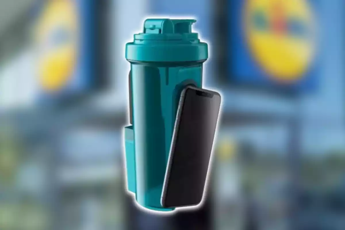 Un got mesclador de color verd amb un telèfon mòbil recolzat al costat, amb un fons desenfocat que mostra un logotip groc i blau. Un got mesclador de color verd amb un telèfon mòbil recolzat al costat, amb un fons desenfocat que mostra un logotip groc i blau.