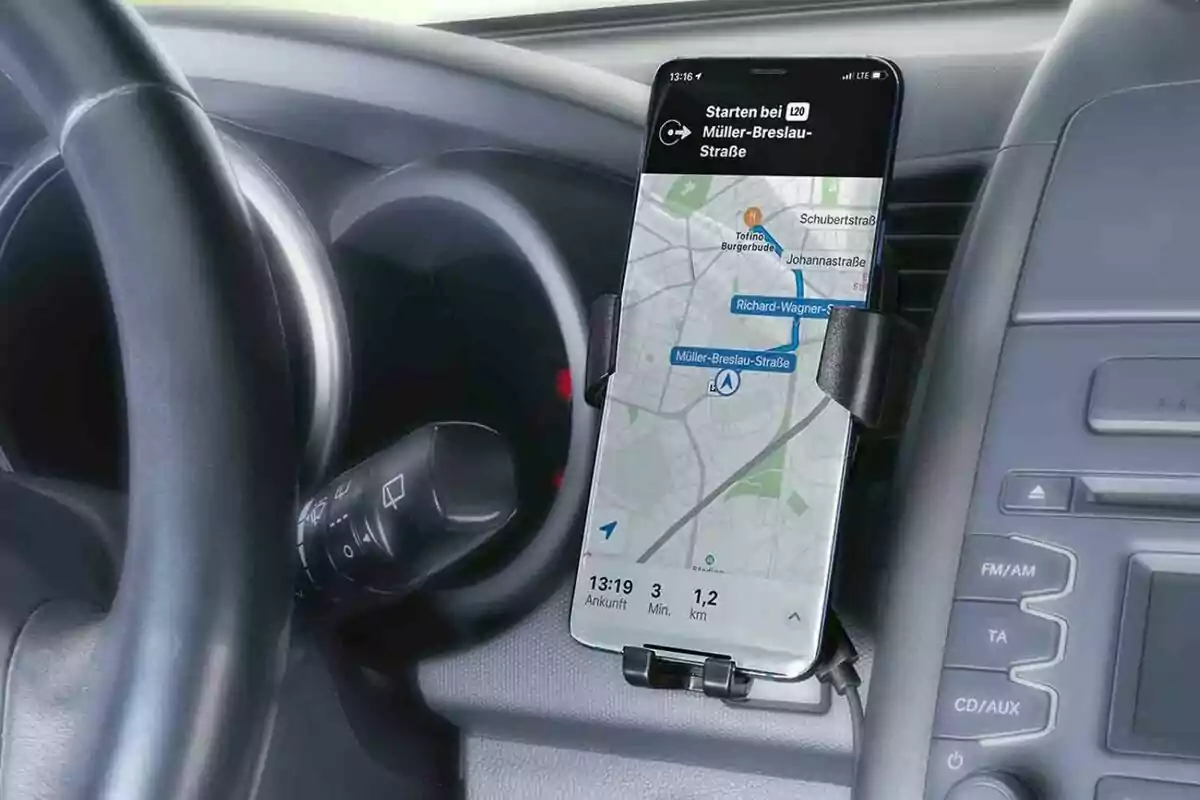 Un telèfon mòbil amb una aplicació de navegació GPS està muntat al tauler d'un automòbil al costat del volant. Un telèfon mòbil amb una aplicació de navegació GPS està muntat al tauler d'un automòbil al costat del volant.