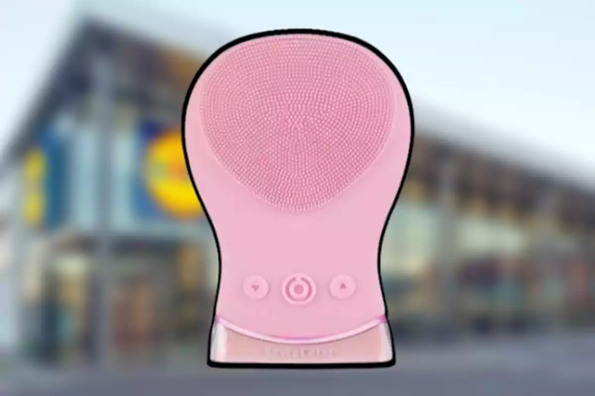 Dispositiu de neteja facial de silicona rosa amb botons de control a un fons desenfocat d'una botiga. Dispositiu de neteja facial de silicona rosa amb botons de control a un fons desenfocat d'una botiga.
