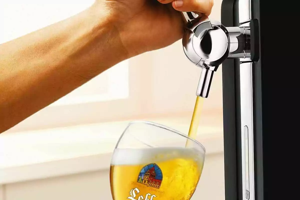 Mà servint cervesa d'un dispensador en un got. Mà servint cervesa d'un dispensador en un got.