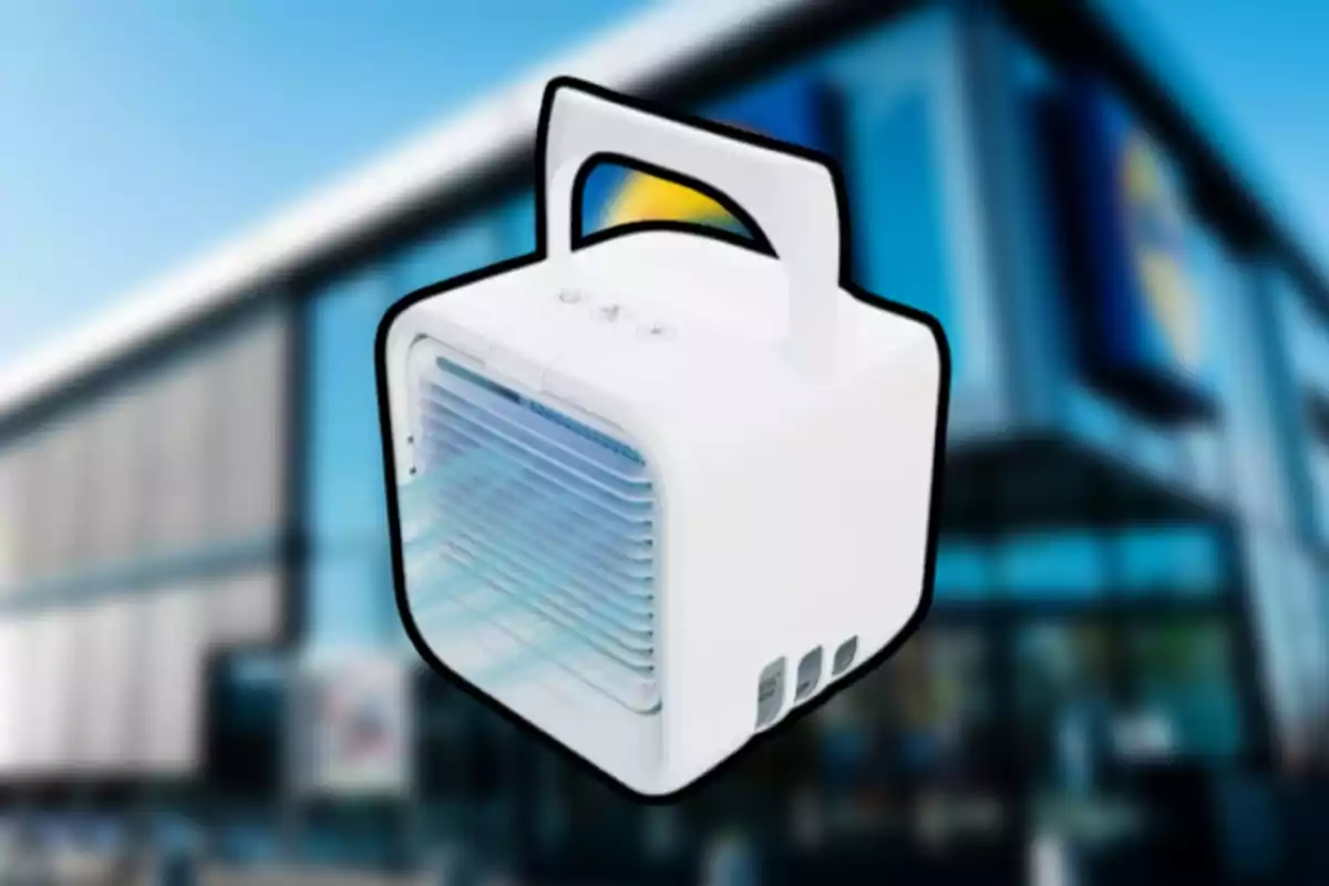 Petit refrigerador d’aire portàtil blanc amb nansa sobre un fons d’edifici desenfocat Petit refrigerador d’aire portàtil blanc amb nansa sobre un fons d’edifici desenfocat