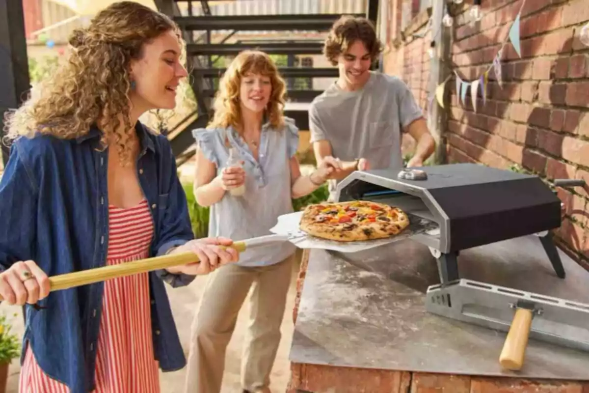 Persones gaudint d'una pizza acabada de coure en un forn a l'aire lliure. Persones gaudint d'una pizza acabada de coure en un forn a l'aire lliure.