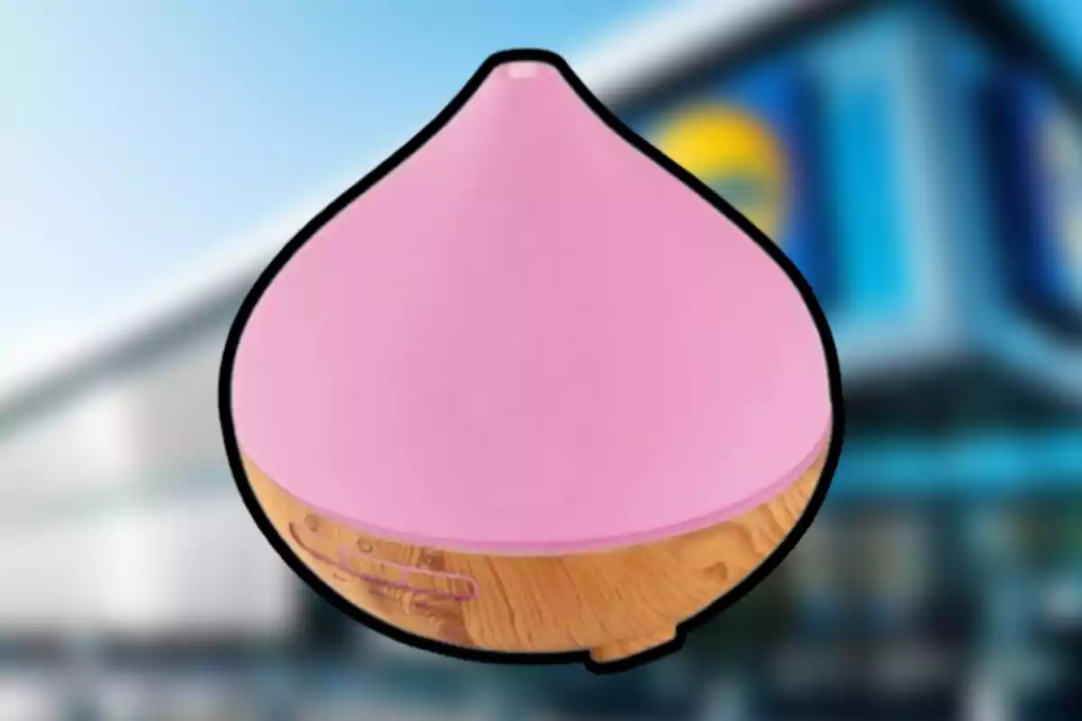 Un difusor d'aroma amb forma de gota, color rosa a la part superior i base de fusta, sobre un fons desenfocat d'un edifici. Un difusor d'aroma amb forma de gota, color rosa a la part superior i base de fusta, sobre un fons desenfocat d'un edifici.