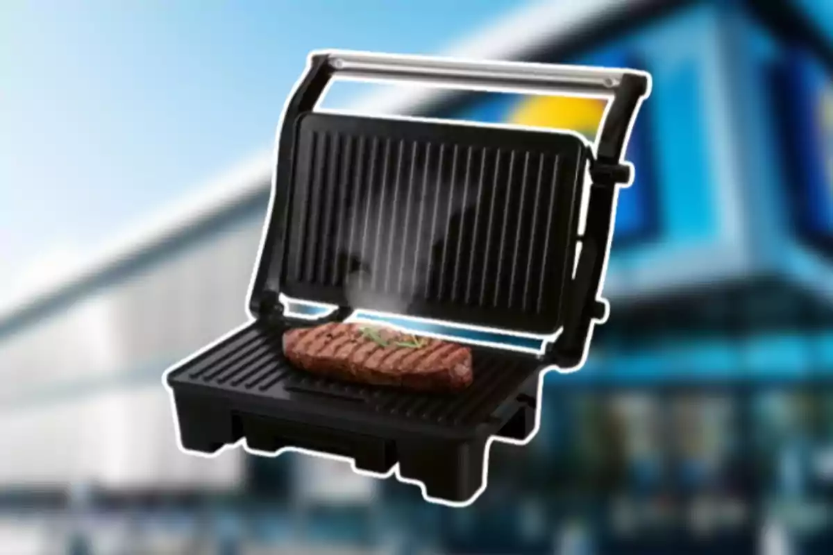 Graella elèctrica negra amb la tapa oberta cuinant un filet sobre un fons desenfocat d’un edifici modern Graella elèctrica negra amb la tapa oberta cuinant un filet sobre un fons desenfocat d’un edifici modern