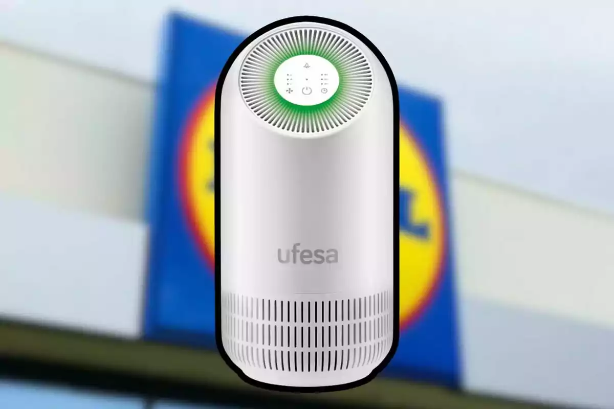 Un purificador d'aire blanc de la marca Ufesa amb un disseny cilíndric i un panell de control a la part superior, davant d'un fons desenfocat d'un cartell de supermercat. Un purificador d'aire blanc de la marca Ufesa amb un disseny cilíndric i un panell de control a la part superior, davant d'un fons desenfocat d'un cartell de supermercat.