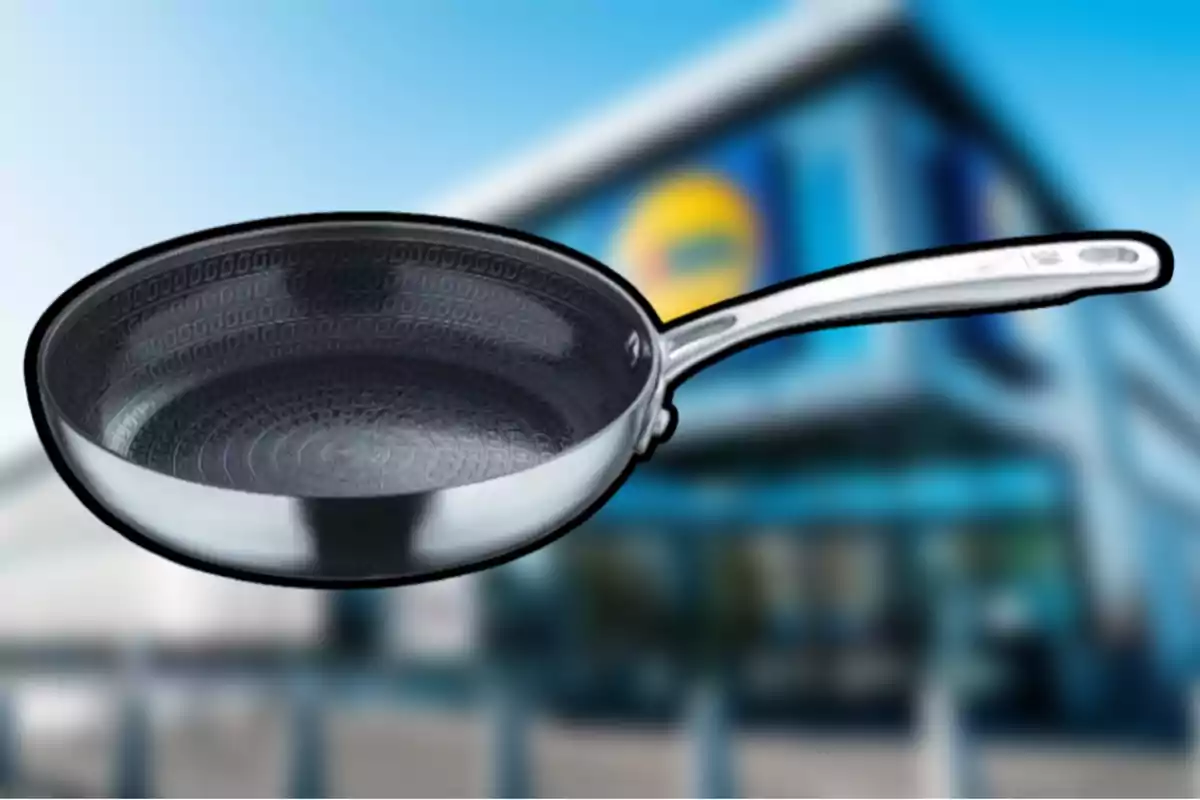 Paella de metall amb fons texturitzat i mànec llarg davant d'un edifici borros. Paella de metall amb fons texturitzat i mànec llarg davant d'un edifici borros.