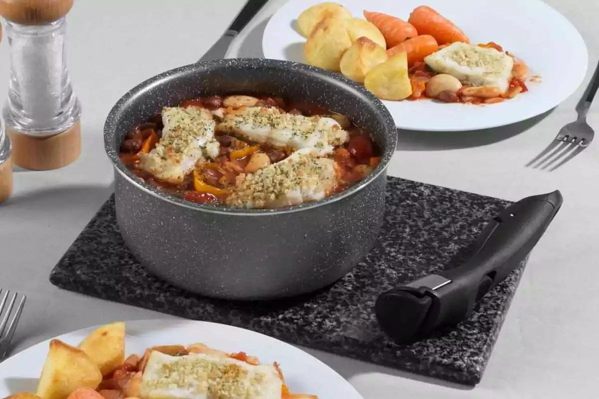 Una olla amb guisat de peix i verdures acompanyada de plats amb patates i pastanagues sobre una taula. Una olla amb guisat de peix i verdures acompanyada de plats amb patates i pastanagues sobre una taula.
