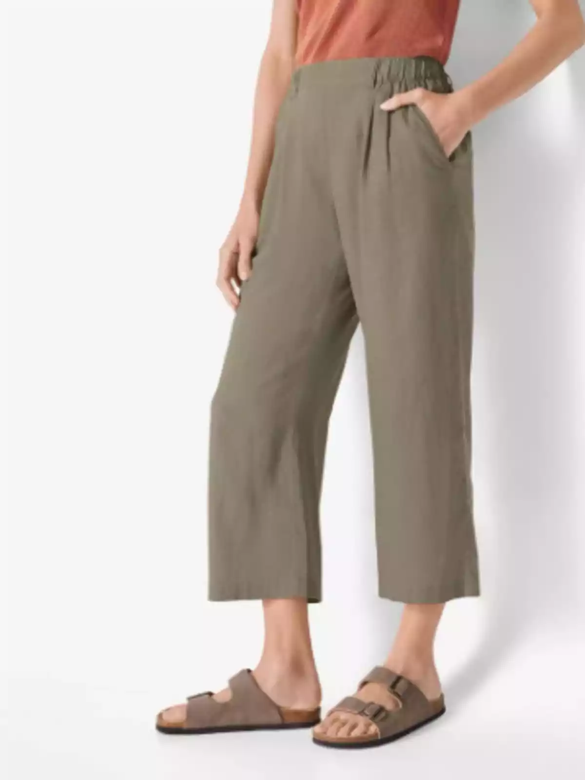 Persona vestint pantalons amples de color verd oliva, samarreta de tirants color terracota i sandàlies marrons Persona vestint pantalons amples de color verd oliva, samarreta de tirants color terracota i sandàlies marrons