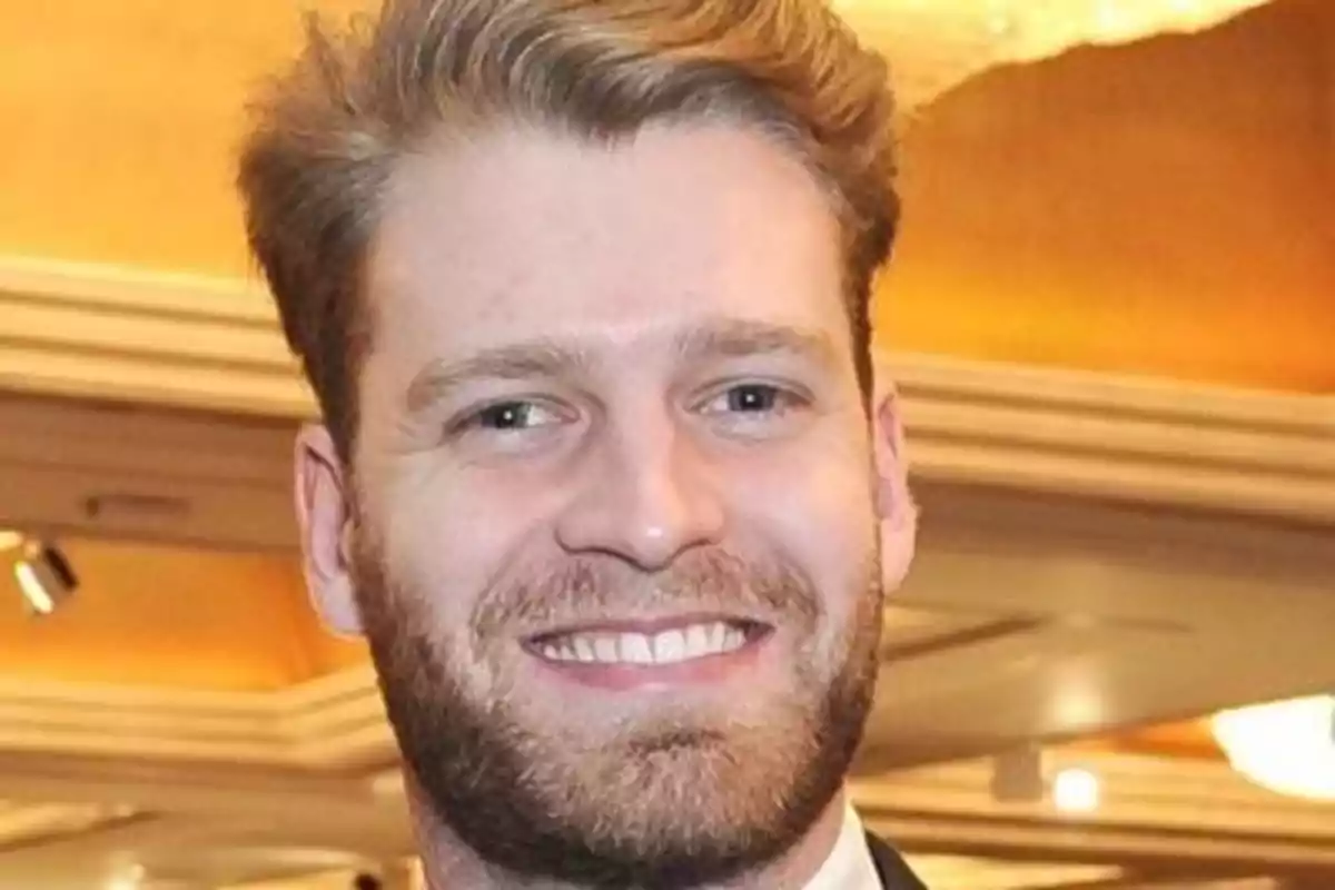 Louis Spencer smiling with a beard and light hair in a well-lit indoor setting.