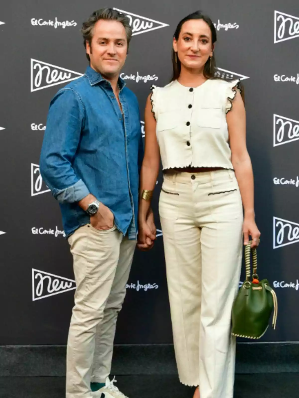 Álvaro López Huerta i Lucía Pombo posen drets en un esdeveniment amb un fons de logotips; ell porta una camisa texana i uns pantalons clars, ella vesteix un conjunt beix sense mànigues i porta una bossa verda. Álvaro López Huerta i Lucía Pombo posen drets en un esdeveniment amb un fons de logotips; ell porta una camisa texana i uns pantalons clars, ella vesteix un conjunt beix sense mànigues i porta una bossa verda.