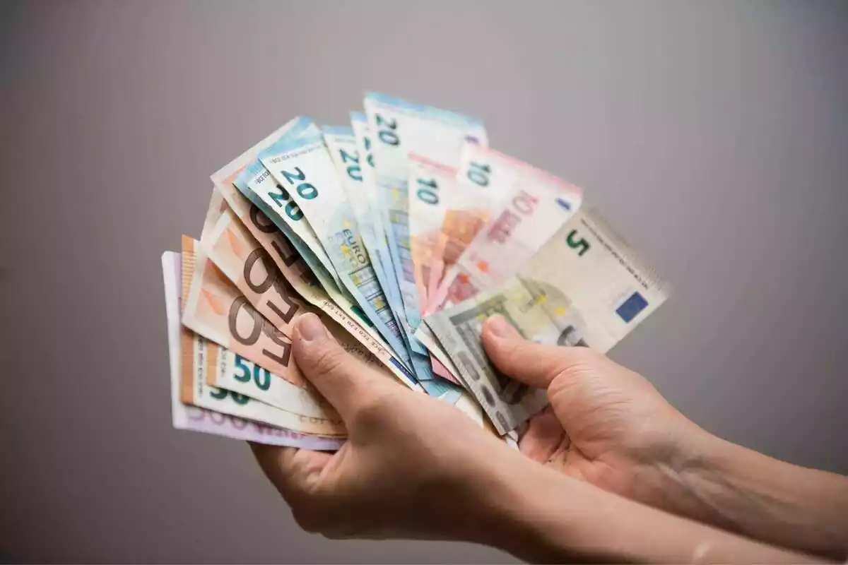 Dos mans d'una persona mostrant diferents tipus de bitllets d'euro en forma de ventall