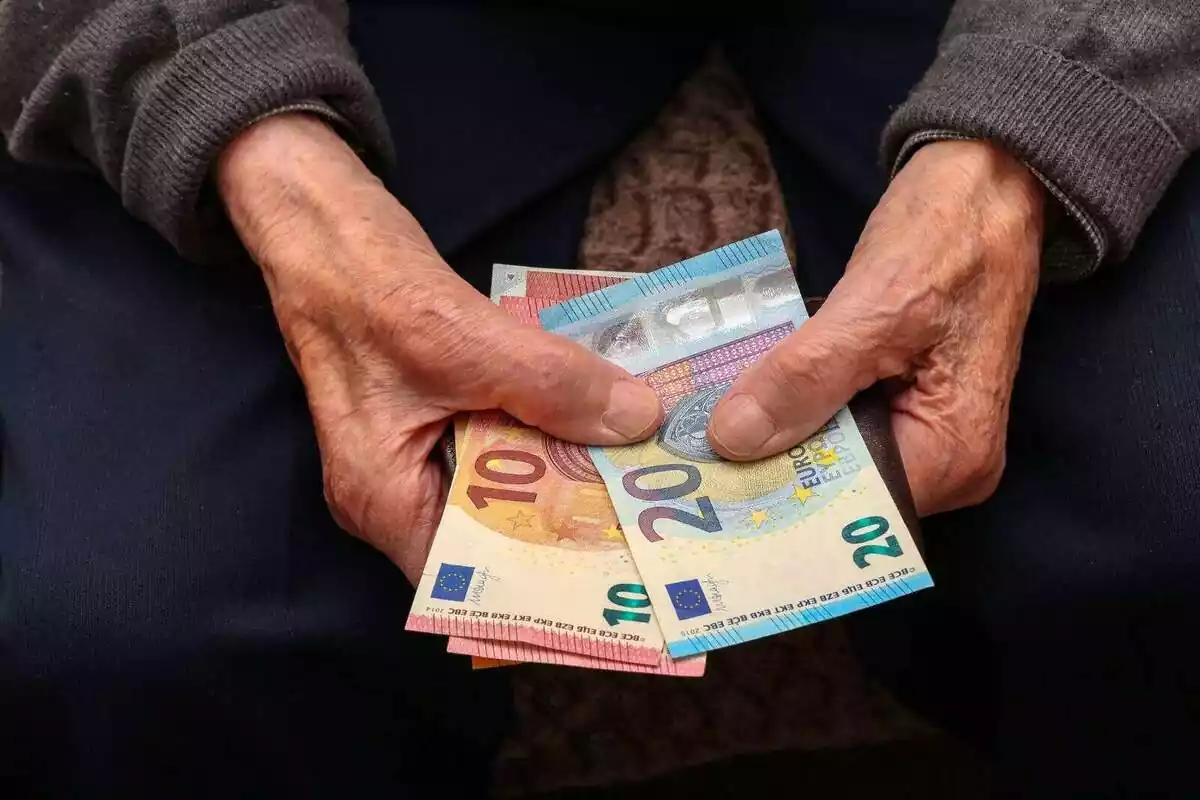 Les mans d'una persona gran agafant diversos bitllets d'euro