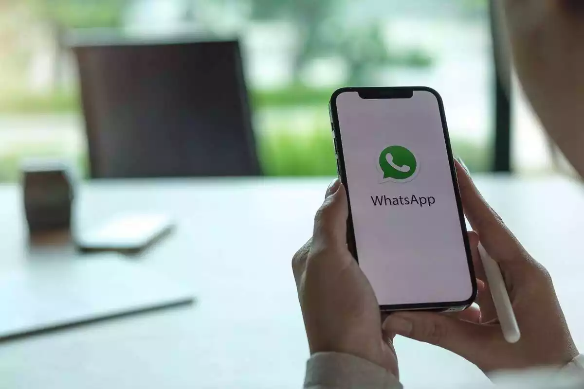 Unes mans subjectant un mòbil i l'aplicació de WhatsApp oberta