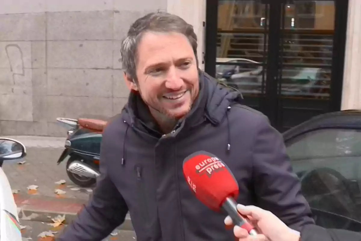 Plànol mitjà de Manuel Martos somrient amb jaqueta fosca és entrevistat al carrer per un micròfon d'Europa Press.