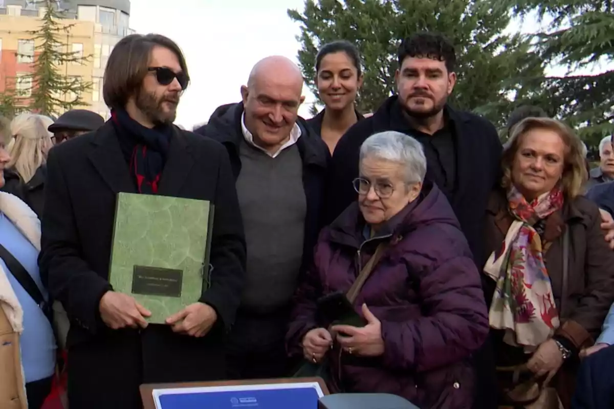 Manuel Velasco, Paco Marsó i la resta de família posant a l'aire lliure, algunes sostenint documents i d'altres somrient, amb arbres i edificis de fons.