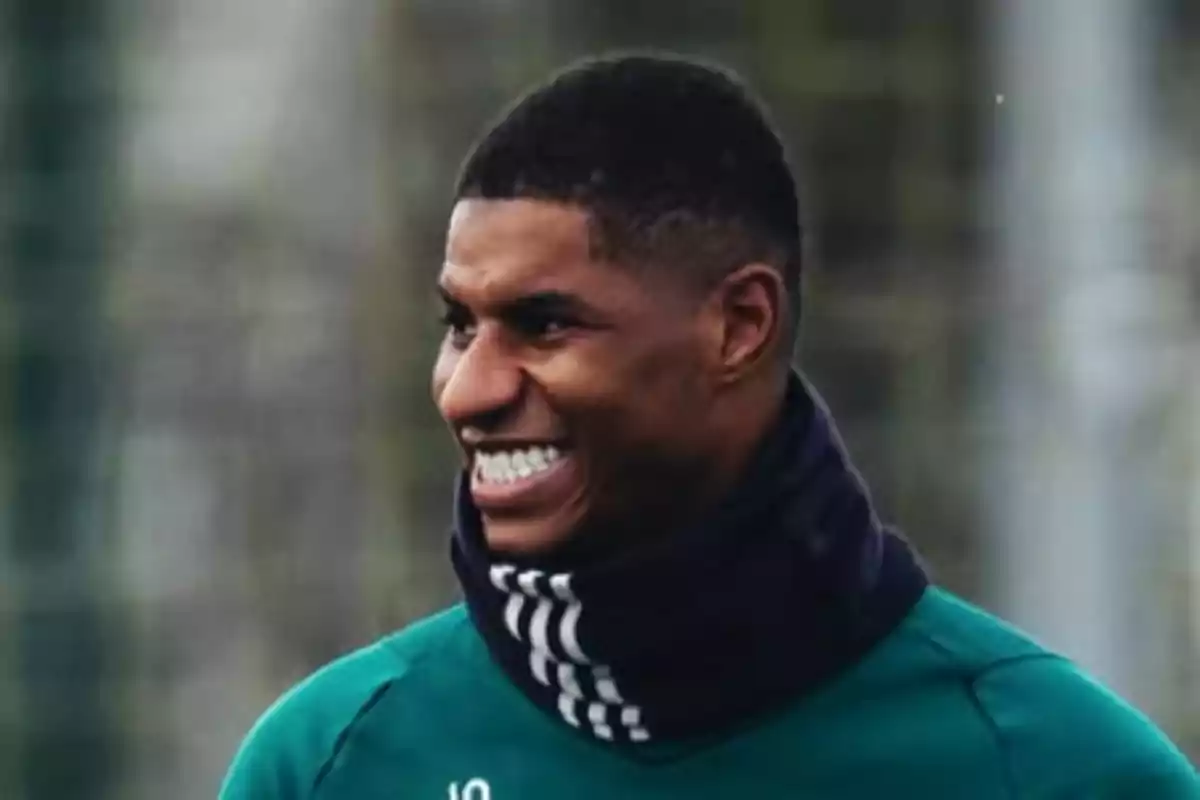 A man smiling while wearing a scarf and a green t-jersey. A man smiling while wearing a scarf and a green t-jersey.
