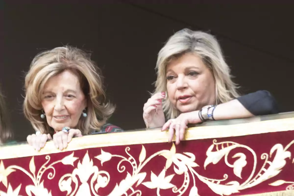 María Teresa Campos y Terelu Campos observando desde un balcón decorado con un tapiz rojo y dorado. María Teresa Campos y Terelu Campos observando desde un balcón decorado con un tapiz rojo y dorado.