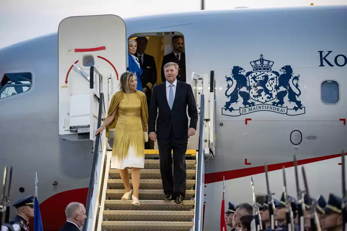 Máxima y Guillermo de Holanda elegantemente vestida desciende de un avión oficial mientras son recibidos por una guardia de honor Máxima y Guillermo de Holanda elegantemente vestida desciende de un avión oficial mientras son recibidos por una guardia de honor