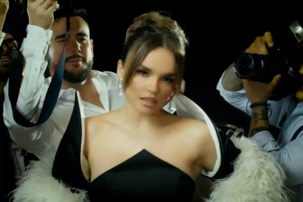 Melody amb un elegant vestit negre i un abric de plomes blanques és fotografiada per diversos fotògrafs en un ambient de catifa vermella al videoclip d'Esa Diva. Melody amb un elegant vestit negre i un abric de plomes blanques és fotografiada per diversos fotògrafs en un ambient de catifa vermella al videoclip d'Esa Diva.