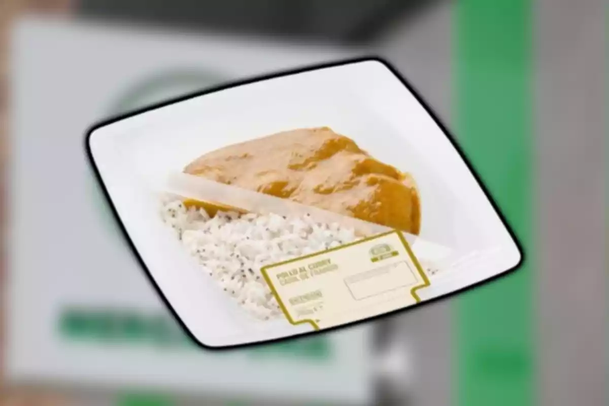 Un plat de menjar que conté arròs blanc i pollastre al curri, presentat en un envàs de plàstic amb una etiqueta. Un plat de menjar que conté arròs blanc i pollastre al curri, presentat en un envàs de plàstic amb una etiqueta.