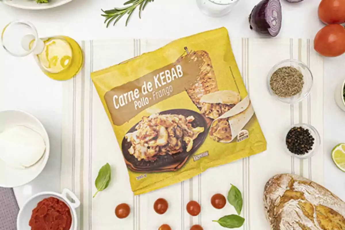 Paquete de carne de kebab de pollo rodeado de ingredientes como aceite, cebolla, tomates, especias, pan y hierbas sobre una mesa. Paquete de carne de kebab de pollo rodeado de ingredientes como aceite, cebolla, tomates, especias, pan y hierbas sobre una mesa.