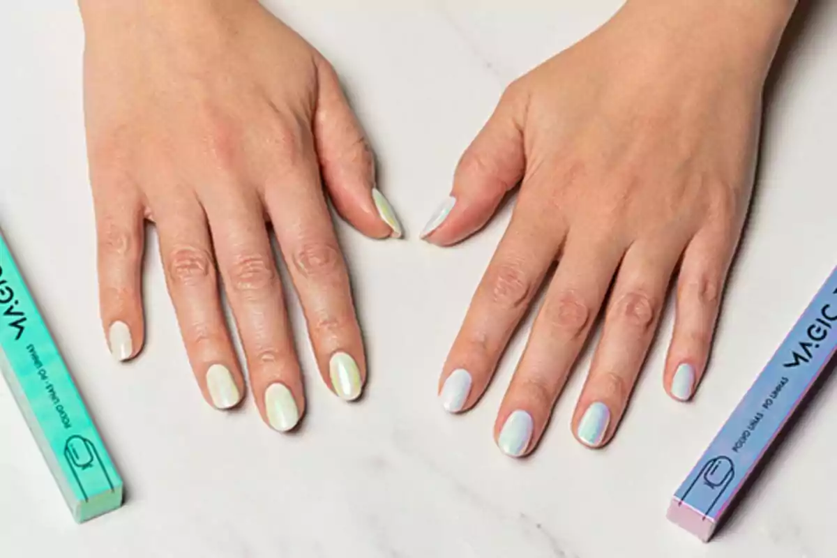 Hands with nails painted in pastel shades on a white surface, next to two boxes of nail files. Hands with nails painted in pastel shades on a white surface, next to two boxes of nail files.