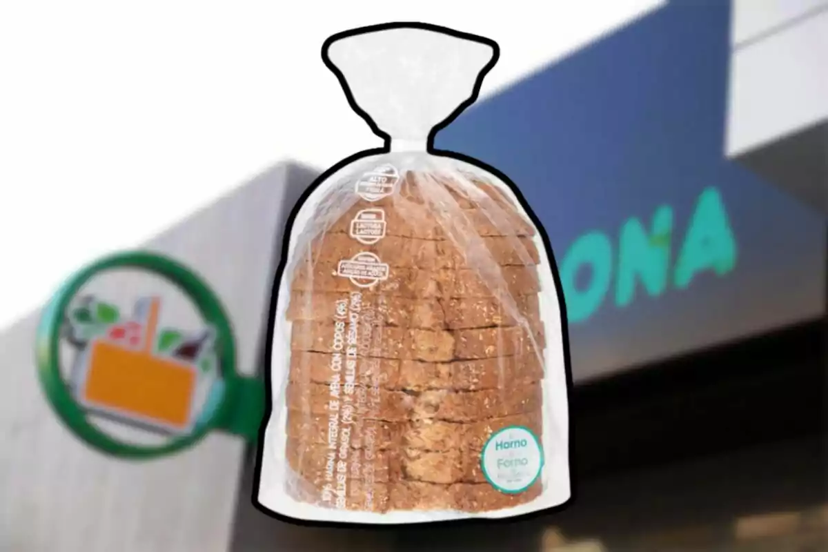 Un paquete de pan integral en rebanadas dentro de una bolsa de plástico transparente con un fondo que muestra un letrero de supermercado. Un paquete de pan integral en rebanadas dentro de una bolsa de plástico transparente con un fondo que muestra un letrero de supermercado.