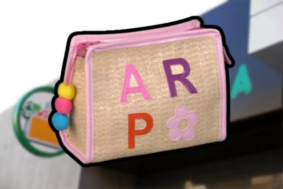A beige fabric bag with pink edges and colorful letters, adorned with colorful pom-poms on one side. A beige fabric bag with pink edges and colorful letters, adorned with colorful pom-poms on one side.
