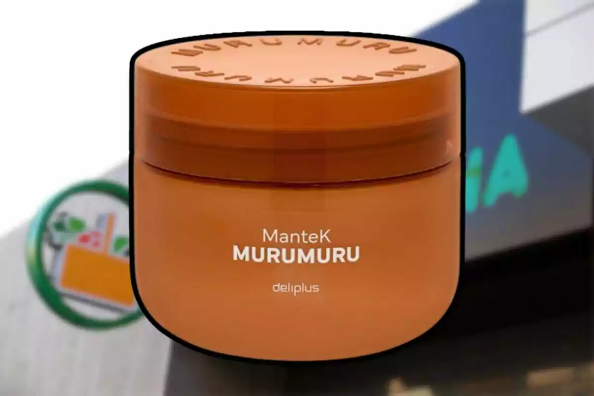 Envàs rodó de color taronja de mantega Murumuru de la marca Deliplus davant d’un cartell de supermercat desenfocat. Envàs rodó de color taronja de mantega Murumuru de la marca Deliplus davant d’un cartell de supermercat desenfocat.