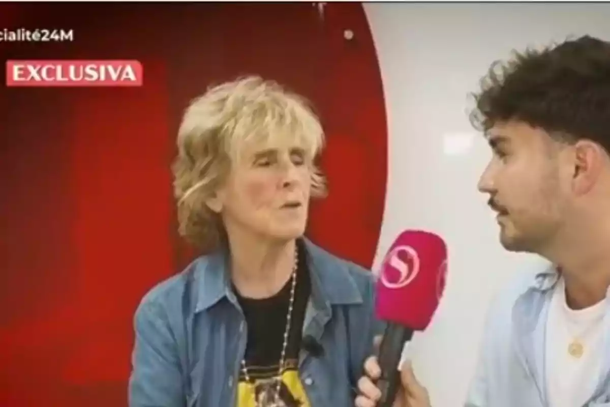 Mercedes Milá sent entrevistada per un jove que sosté un micròfon rosa a 'Socialité' Mercedes Milá sent entrevistada per un jove que sosté un micròfon rosa a 'Socialité'
