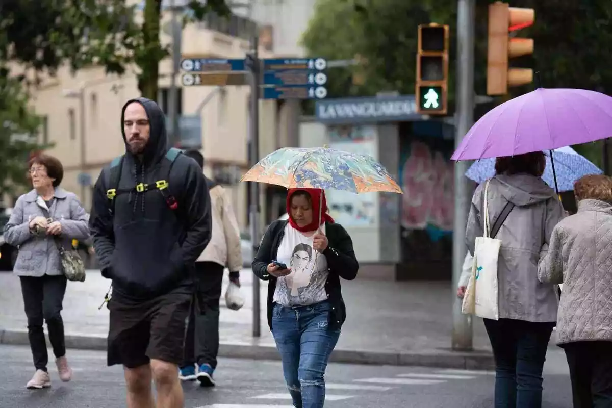 Imatge de diverses persones fugint de la pluja a Barcelona